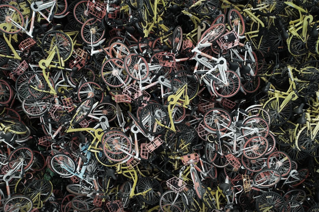 Abandoned bike sharing bicycles piled in chaotic urban waste heap.
