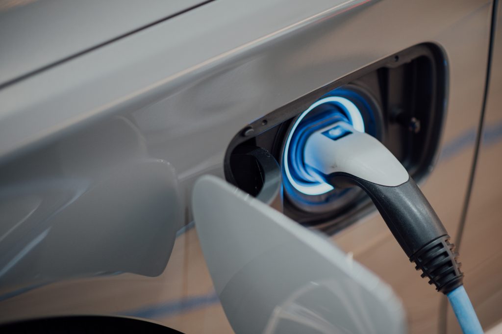Electric vehicle charging plug connected to blue-lit EV charging port.